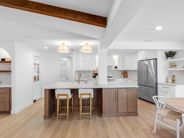 kitchen with decorative backsplash, open shelves, stainless steel appliances, and light wood-style flooring