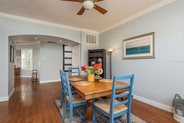 dining area with crown molding, arched walkways, visible vents, and hardwood / wood-style flooring