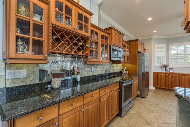 kitchen featuring brown cabinetry, light tile patterned floors, backsplash, and appliances with stainless steel finishes