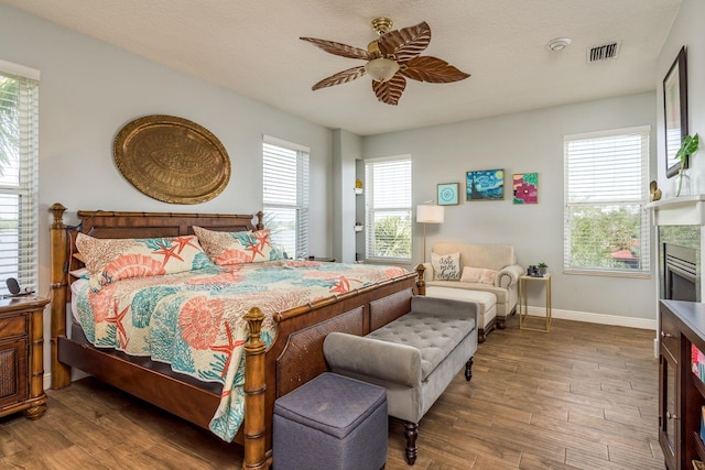 bedroom featuring visible vents, baseboards, wood finished floors, and a fireplace