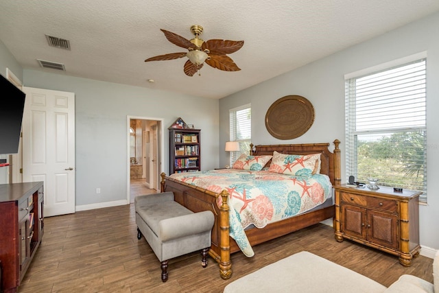 bedroom featuring a textured ceiling, visible vents, dark wood finished floors, and baseboards