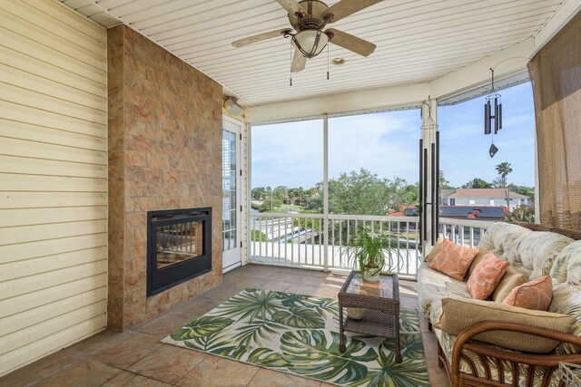 sunroom / solarium with ceiling fan and a tiled fireplace