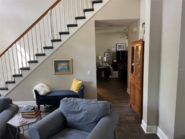 living area featuring baseboards, stairway, and wood tiled floor