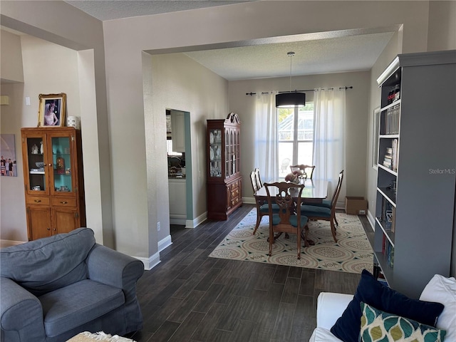 dining room featuring baseboards, a textured ceiling, and dark wood-style floors