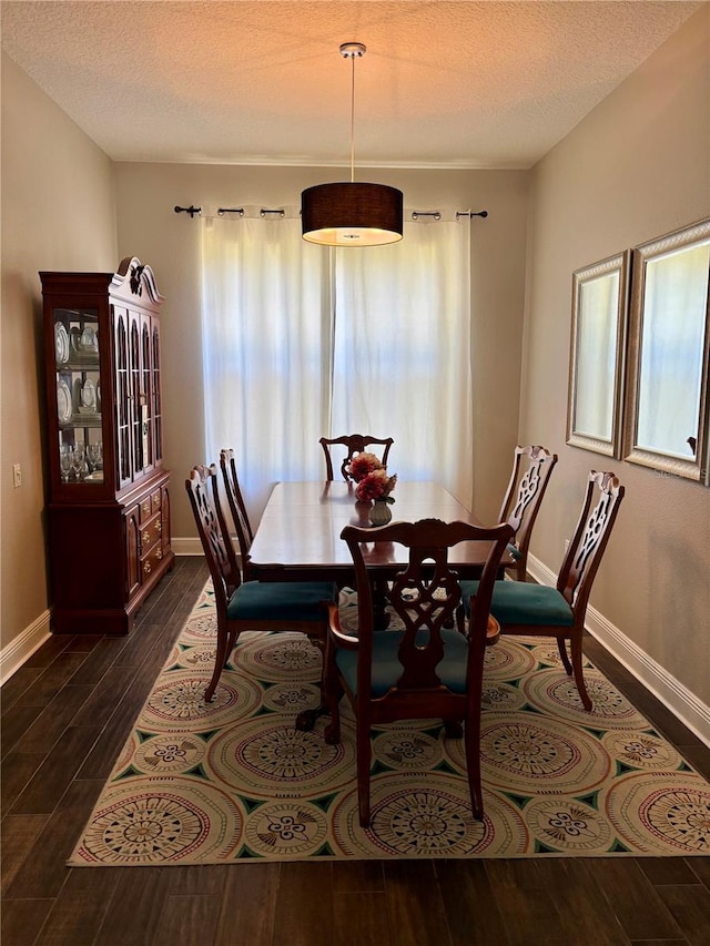 dining area with a textured ceiling, baseboards, and dark wood-style floors