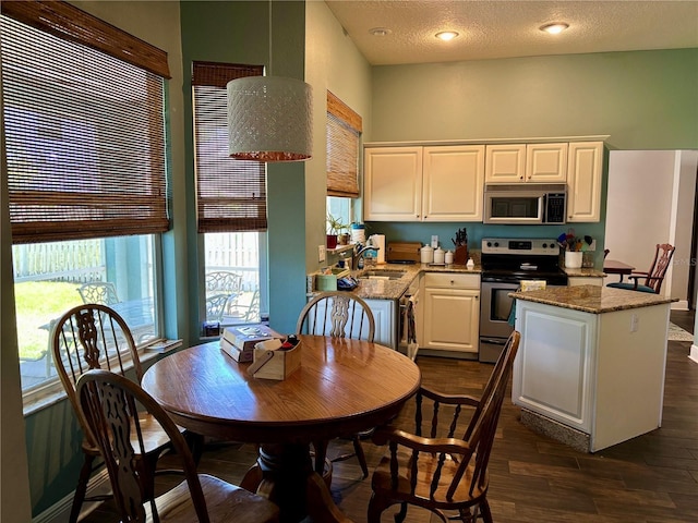 kitchen featuring light stone counters, dark wood finished floors, stainless steel appliances, white cabinetry, and a kitchen island