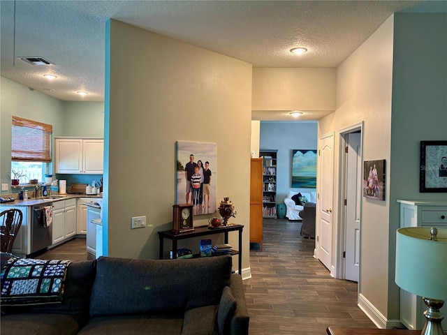 hall featuring a textured ceiling, dark wood finished floors, baseboards, and visible vents