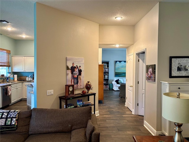 hall with visible vents, dark wood-style flooring, baseboards, a textured ceiling, and a sink
