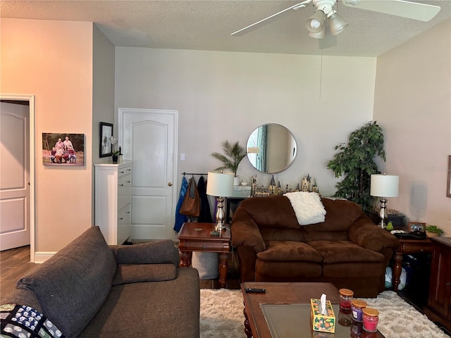 living area with a ceiling fan, a textured ceiling, and wood finished floors