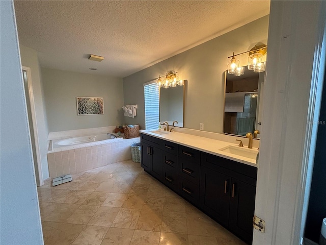 full bathroom with double vanity, a textured ceiling, a sink, and a garden tub
