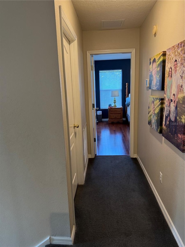 corridor featuring baseboards and dark carpet