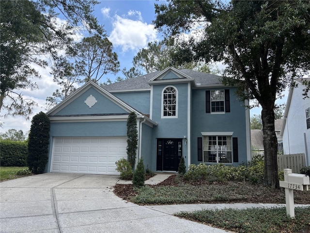 traditional home featuring fence, an attached garage, driveway, and stucco siding