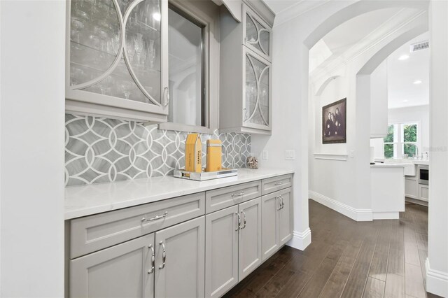 2604 S Bryant Cir, Tampa, FL 33629 - bar area featuring tasteful backsplash, arched walkways, baseboards, dark wood finished floors, and crown molding