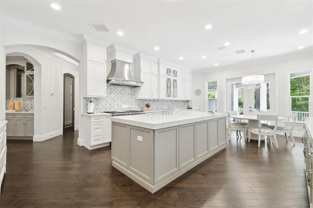2604 S Bryant Cir, Tampa, FL 33629 - kitchen featuring wall chimney range hood, crown molding, decorative backsplash, a center island, and white cabinets