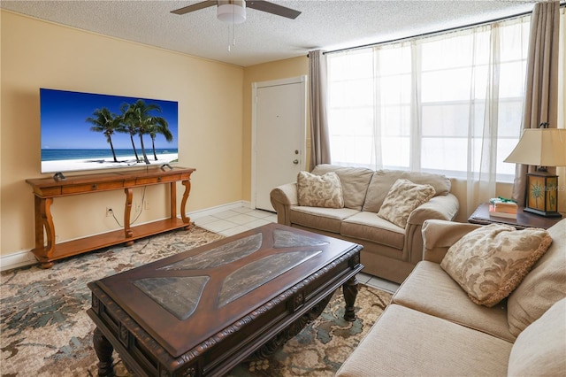 living area featuring baseboards, ceiling fan, and a textured ceiling