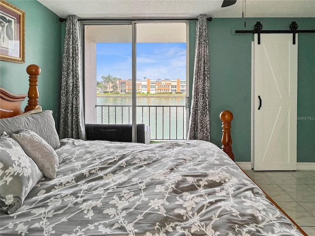 tiled bedroom with a wall of windows, a barn door, a water view, and access to exterior