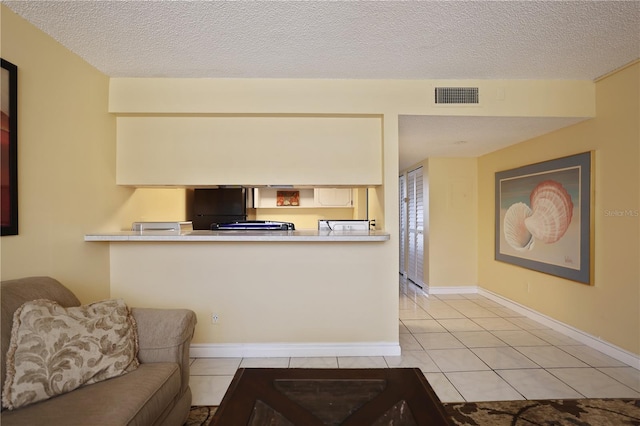 living area with baseboards, visible vents, a textured ceiling, and tile patterned flooring