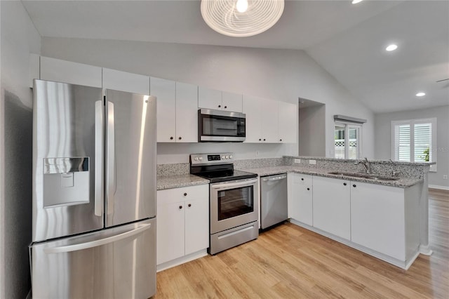 11932 Whisper Creek Dr, Riverview, FL 33569 - kitchen featuring stainless steel appliances, a sink, lofted ceiling, light wood-type flooring, and a peninsula