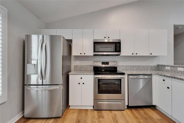 11932 Whisper Creek Dr, Riverview, FL 33569 - kitchen with appliances with stainless steel finishes, vaulted ceiling, white cabinets, light wood-style floors, and light stone counters