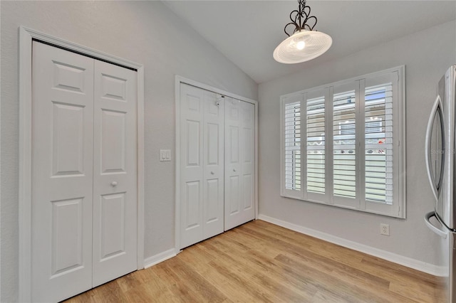 11932 Whisper Creek Dr, Riverview, FL 33569 - unfurnished bedroom featuring freestanding refrigerator, vaulted ceiling, light wood finished floors, baseboards, and two closets