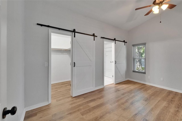 11932 Whisper Creek Dr, Riverview, FL 33569 - unfurnished bedroom with a barn door, light wood finished floors, a walk in closet, vaulted ceiling, and baseboards