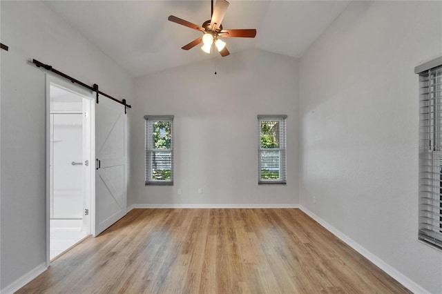 11932 Whisper Creek Dr, Riverview, FL 33569 - unfurnished bedroom featuring a barn door, light wood-type flooring, lofted ceiling, and baseboards