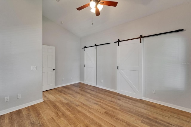 11932 Whisper Creek Dr, Riverview, FL 33569 - unfurnished bedroom featuring a barn door, light wood-style floors, lofted ceiling, baseboards, and ceiling fan