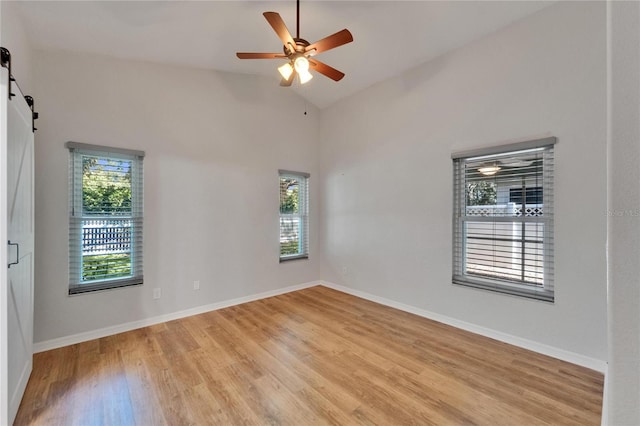11932 Whisper Creek Dr, Riverview, FL 33569 - empty room featuring plenty of natural light, a barn door, light wood-style flooring, high vaulted ceiling, and a ceiling fan