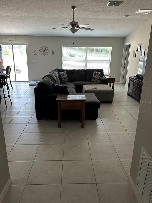 living area with ceiling fan, light tile patterned flooring, and plenty of natural light