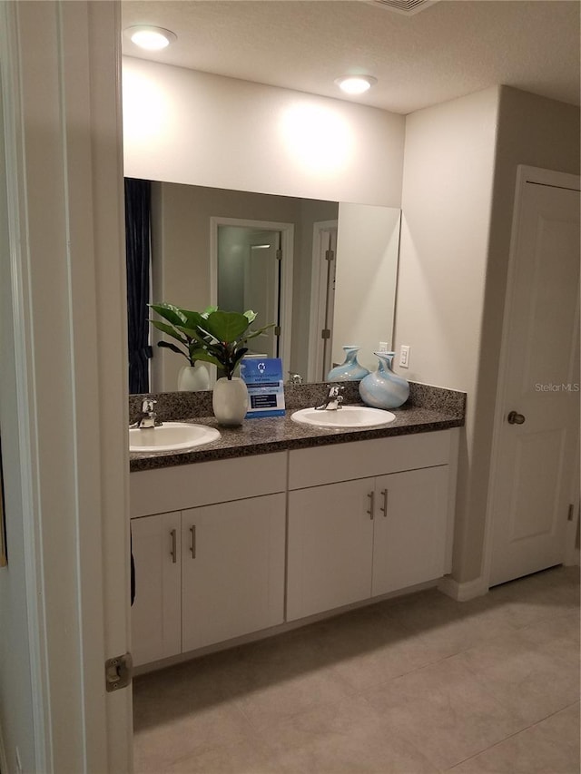 bathroom featuring tile patterned flooring, double vanity, and a sink