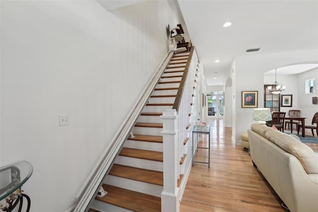 stairway with visible vents, arched walkways, an inviting chandelier, recessed lighting, and wood finished floors