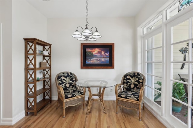living area with light wood-style floors, a notable chandelier, and baseboards