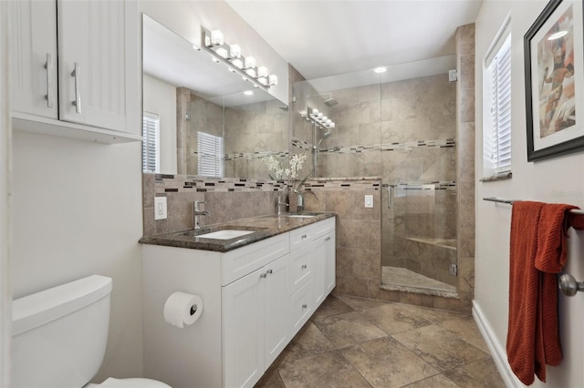 full bath featuring a shower stall, toilet, double vanity, and a sink