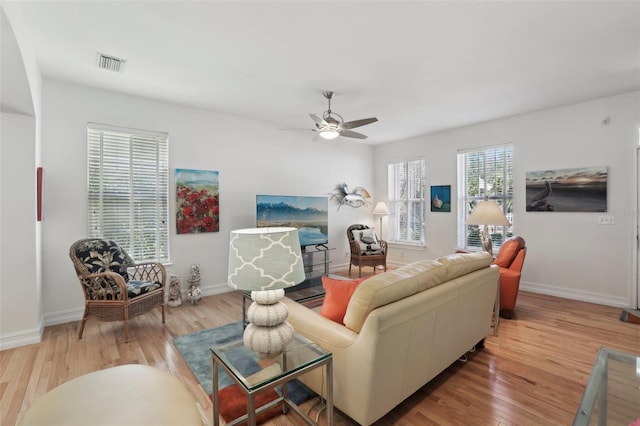 living room featuring baseboards, visible vents, wood finished floors, and a ceiling fan