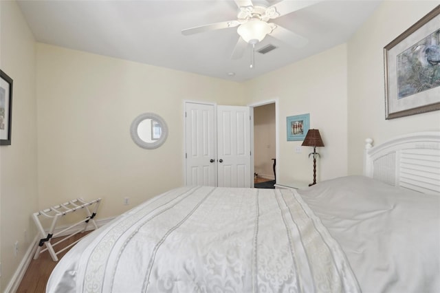 bedroom with a ceiling fan, visible vents, wood finished floors, and baseboards