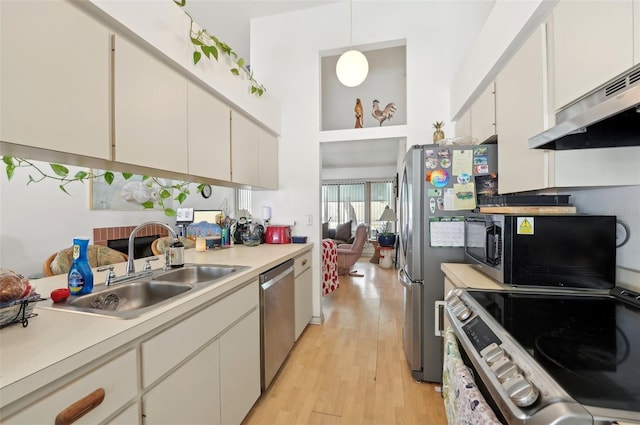 3093 Woodpine Cir, Sarasota, FL 34231 - kitchen with light wood-type flooring, a sink, light countertops, under cabinet range hood, and stainless steel appliances
