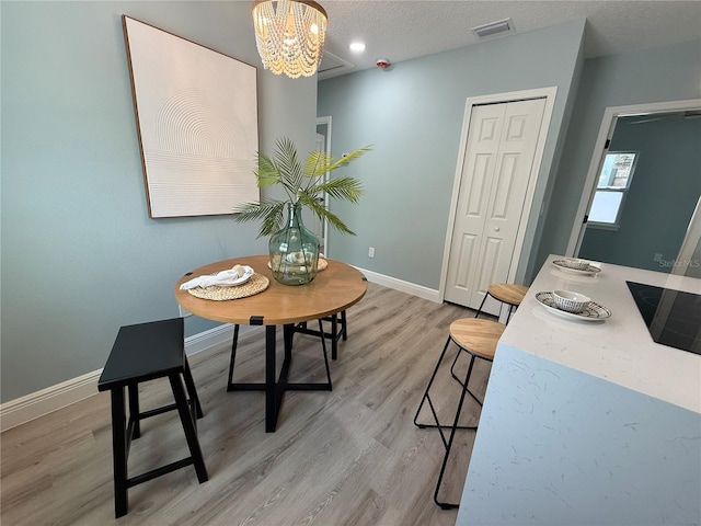 110 Kenwood Ave, Clearwater, FL 33755 - dining area featuring a chandelier, baseboards, light wood-style floors, and a textured ceiling