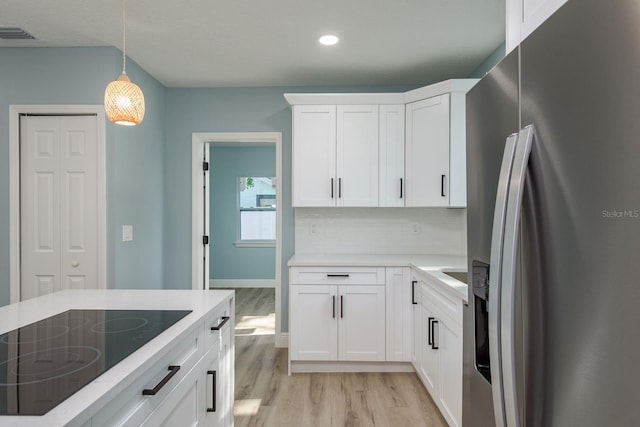 110 Kenwood Ave, Clearwater, FL 33755 - kitchen featuring stainless steel refrigerator with ice dispenser, black electric stovetop, light wood-type flooring, pendant lighting, and white cabinetry