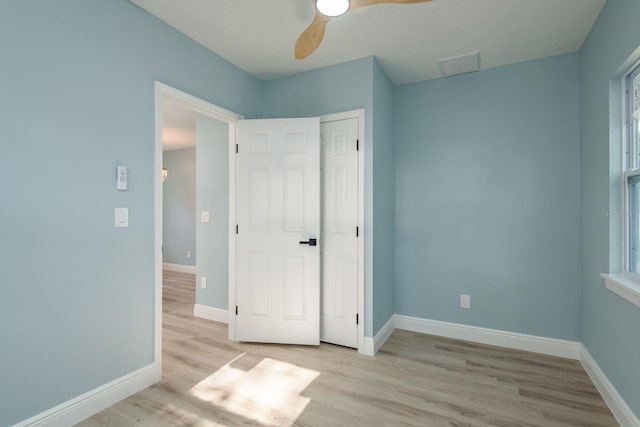 110 Kenwood Ave, Clearwater, FL 33755 - unfurnished bedroom with light wood finished floors, baseboards, a ceiling fan, and multiple windows