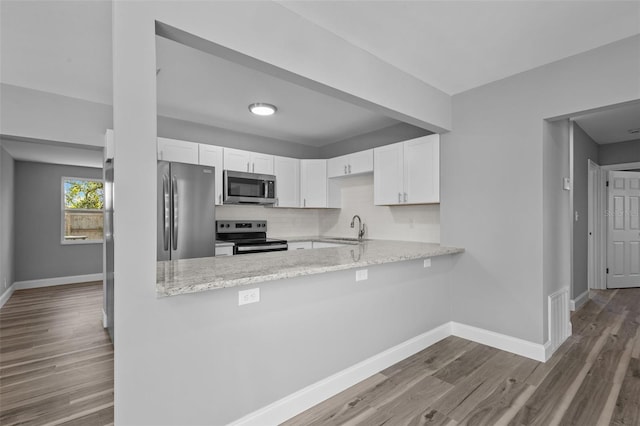 660 Palm Ave, Tarpon Springs, FL 34689 - kitchen featuring white cabinetry, a sink, stainless steel appliances, baseboards, and a peninsula