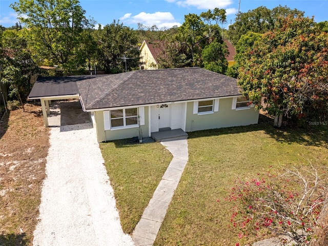 660 Palm Ave, Tarpon Springs, FL 34689 - view of front facade with stucco siding, an attached carport, driveway, roof with shingles, and a front yard