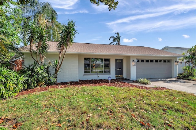 ranch-style house with a front yard, a garage, brick siding, driveway, and roof with shingles