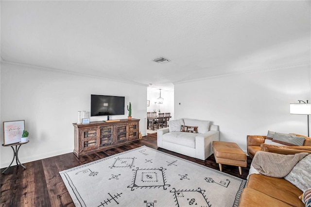 living room with a notable chandelier, crown molding, visible vents, baseboards, and wood finished floors