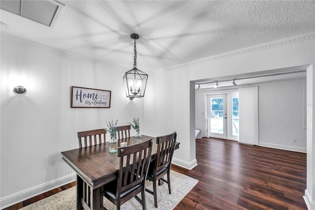 dining room featuring a textured ceiling, visible vents, ornamental molding, and dark wood finished floors