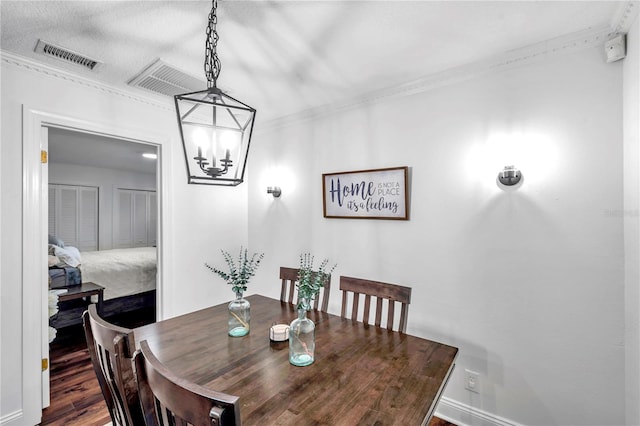 dining area with crown molding, an inviting chandelier, wood finished floors, and visible vents
