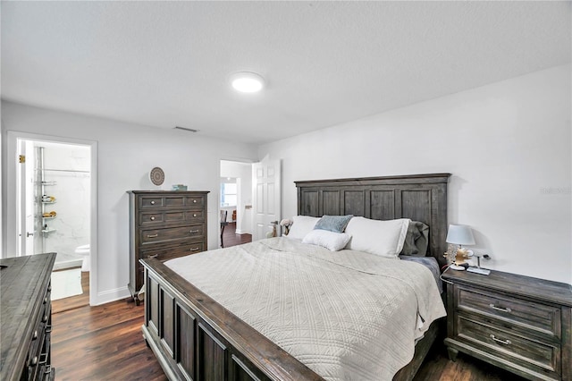 bedroom featuring dark wood-style floors, ensuite bathroom, visible vents, and baseboards