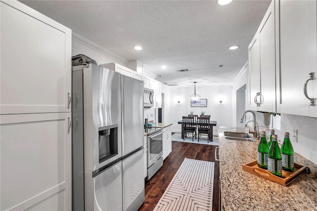 kitchen with recessed lighting, stainless steel appliances, white cabinets, a sink, and a textured ceiling