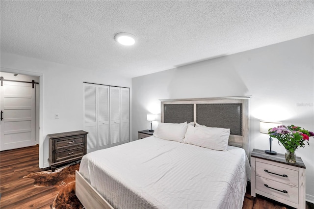 bedroom with wood finished floors, a barn door, a closet, and a textured ceiling