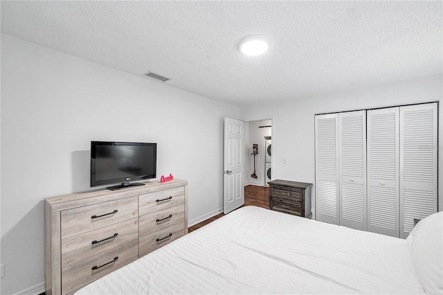 bedroom featuring baseboards, visible vents, a textured ceiling, and a closet