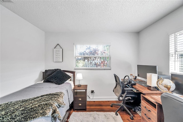 bedroom with a textured ceiling, wood finished floors, and baseboards